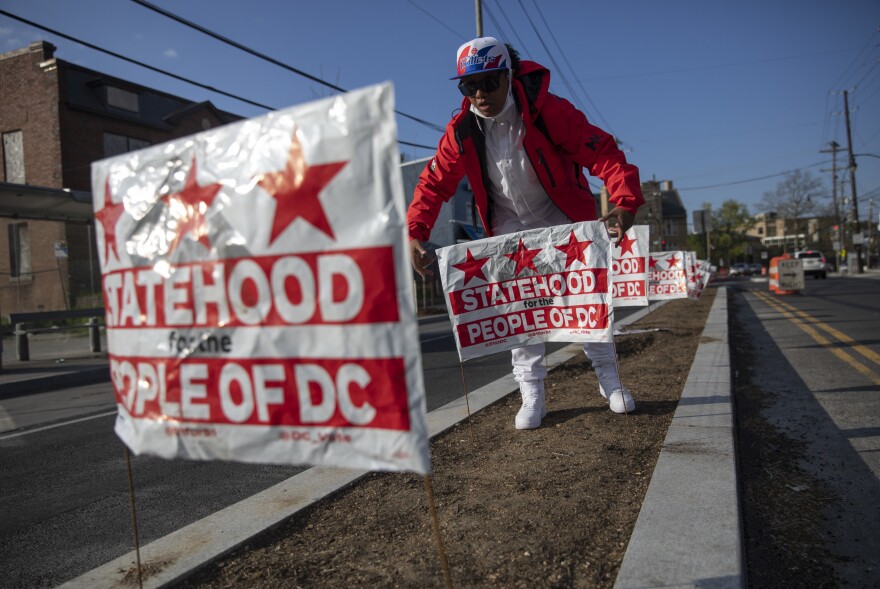 Jasmine Joyner places signs at Martin Luther King Jr. Ave & Malcolm X Ave SE in Washington, D.C.