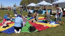 Dozens of families spend a cool-but-sunny Monday at Gatton Park. Some climb play structures, while others toss bean bags. A group of very small ones sit on a parachute in a read-along of "The Very Hungry Caterpillar."