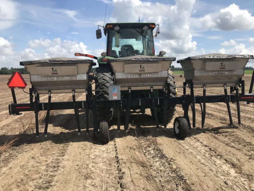 A “Banding Rig” machine applies dry fertilizer to a dirt field.