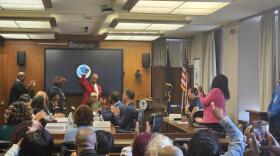 New Buffalo Public Schools Board of Education Member Roscoe Henderson III, in red with fist raised, addresses audience members during his swearing-in ceremony