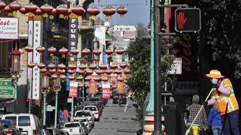 In this Jan. 31, 2020, file photo, a masked worker cleans a street in the Chinatown district in San Francisco. Police and volunteers have increased their street presence after a series of violent attacks against older Asian residents in Bay Area cities stoked fear and subdued the celebratory mood leading up to the Lunar New Year. (AP Photo/Ben Margot, File)