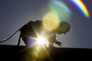 FILE - In this July 6, 2010 file photo, a construction worker is backlit from the morning sun while working on a roof in the heat in Chapel Hill, N.C. as temperatures inched into at least the 90s from Maine to Texas and into the Southwest and Death Valley, the mid-Atlantic is embarking on a string of intensely hot days, with temperatures in some places closing in on 100-plus degrees. The combination of global warming and people moving south and west means that by mid-century four to six times more Americans will be sweating through days with extreme heat than just 15 years ago, a new study says. (AP Photo/Gerry Broome, File)