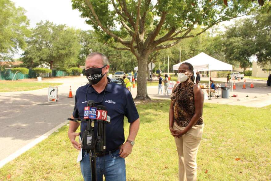 Orlando Mayor Buddy Dyer addresses the media at a testing site in West Orlando as commissioner Regina Hill looks on. Photo: Matthew Peddie, WMFE