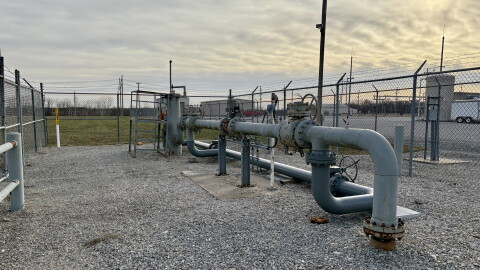 Metal pipes outside a gas plant go into the ground and connect to each other above ground. 
