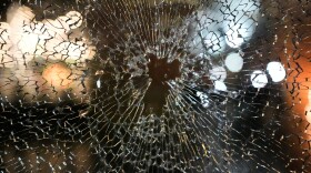 A window is shown shattered with lights reflecting onto the glass.