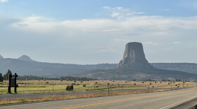 Devils Tower rises in the background, with a road in the foreground.