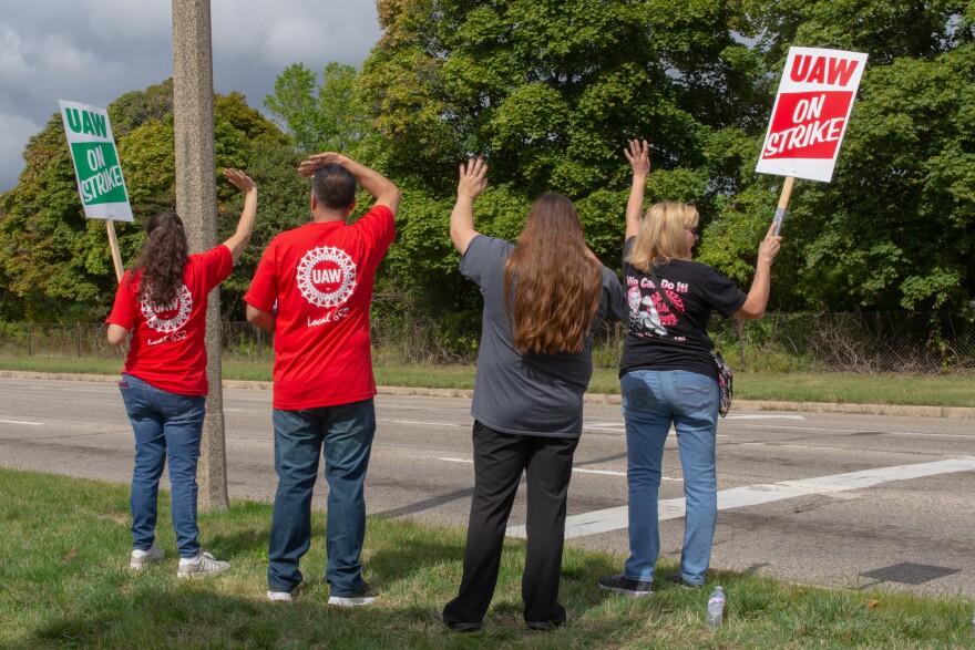 UAW strikers picketing on the side of the road with signs