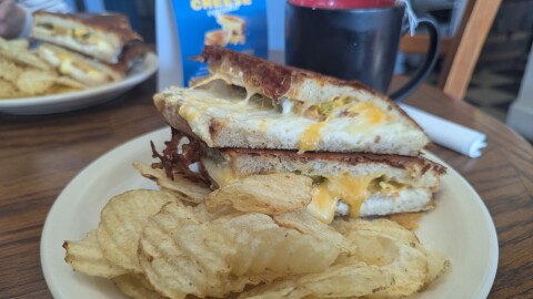 A grilled cheese sandwich on a plate with chips