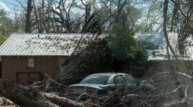 A fallen tree lies in front of a house in Marianna, FL.