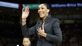A'ja Wilson, center, stands with her parents Eva and Roscoe Wilson as they watch her number be retired during a ceremony before an NCAA college basketball game between South Carolina and Auburn in Columbia, S.C., Sunday, Feb. 2, 2025. (AP Photo/Nell Redmond)