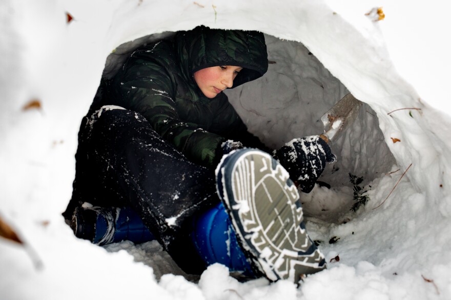 Michael, 12, whose parents asked to not use their last name, carves out an igloo on Friday, Dec. 23, 2022, outside of his home in Benton Park.