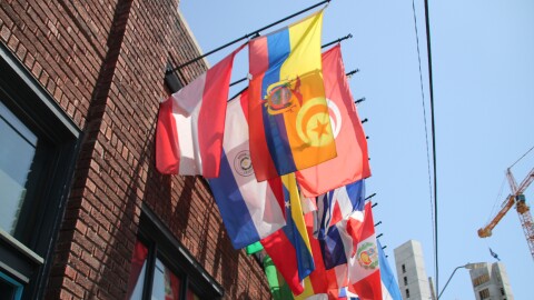 Flags representing different countries are hung at the top of a building.