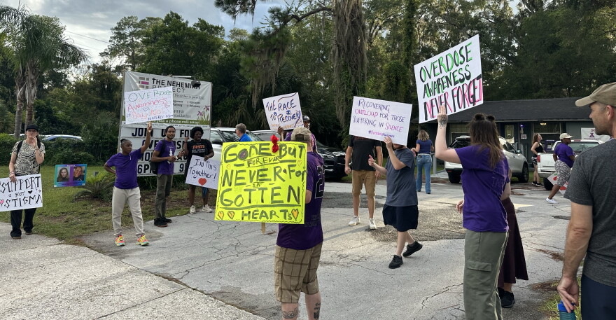 Attendees hold up signs in front of the Nehemiah Project as they support overdose awareness and remember their loved ones. (Mackenzie Davis/WUFT News)