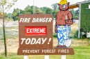A sign next to a Smokey Bear cutout that says "Fire Danger Extreme Today! Prevent Forest Fires."