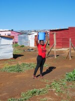 Annah Goba, 20, carries water to her shack in Azania, the name squatters gave to a section of private property they took over in Stellenbosch. Goba said the lack of running water was a challenge, but she couldn't afford to pay rent in crowded Kayamandi township. Her shirt is from the far-left Economic Freedom Fighters party, which encourages supporters to occupy the land of wealthy farm owners.