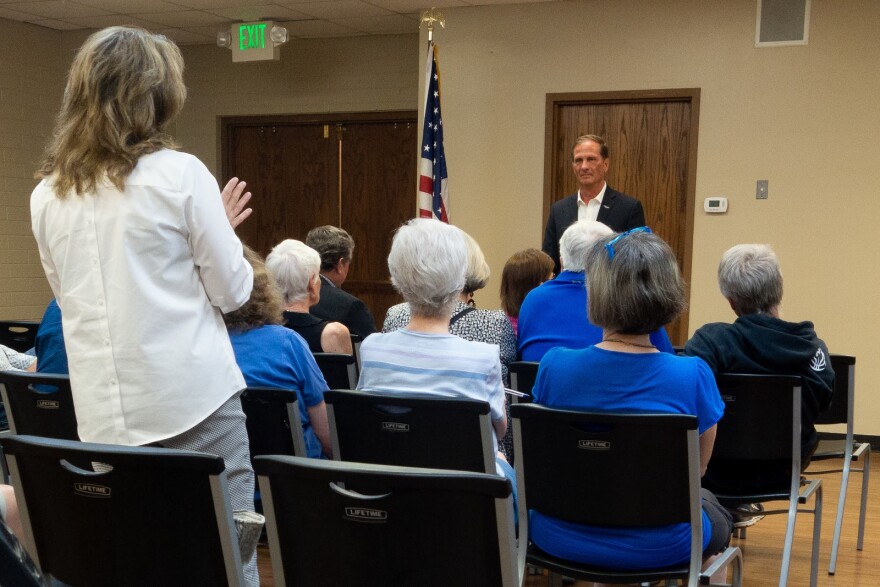 Photo of a constituent questioning Rep. Chris Stewart as several rows of audience members look on.