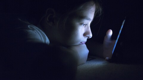 Teenager sending email from smart phone in her bed, Typing text message on smartphone. young cell phone addict teen awake at night in bed using smartphone for chatting