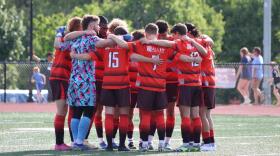Members of The Lansing Common, an amateur soccer club, huddling on the pitch.