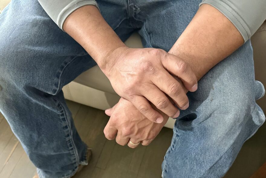 A man sits with hands crossed. Juan, who lives in Sioux City, Iowa, said he's worried for immigrants who are scared of being arrested and deported.