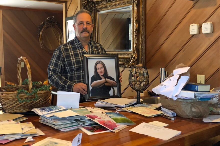 Greg Tatro holds a picture of his daughter, Jenna, who died of an opioid overdose in February. In the foreground are piles of sympathy cards he and his wife have received.