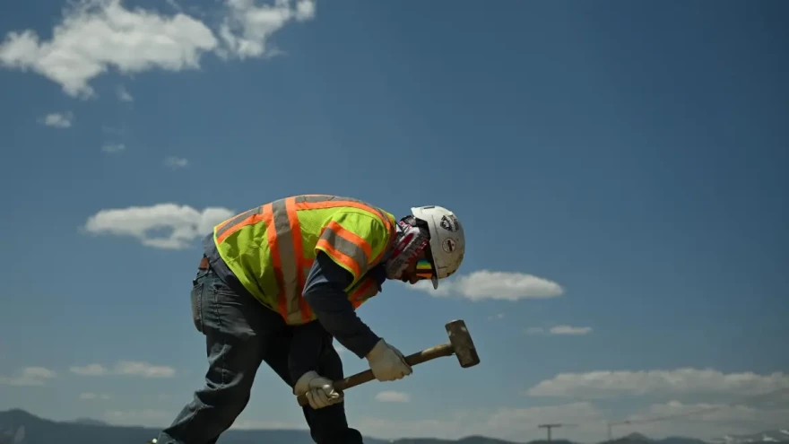 Worker in protective vest using a mallet