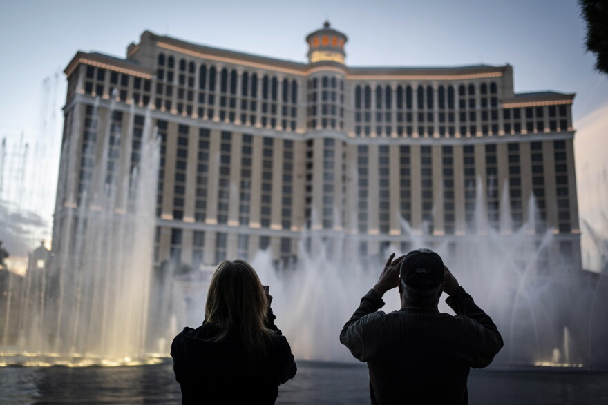 People are silhouetted as they take photos of the fountains at the Bellagio hotel-casino along the Las Vegas Strip, Wednesday, Nov. 11, 2020. 
