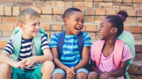 Happy mixed race school kids sit together on staircase