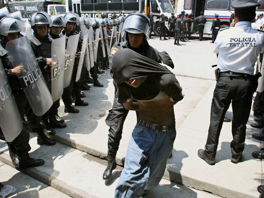 A protester who clashed with state riot police in the town of San Salvador Atenco is taken into the Santiaguito prison in Almoloya de Juarez, Mexico in 2006. Hundreds of police fired tear gas and pushed through human barricades to take control of the town.