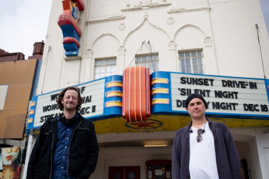 Barak Epstein and Jason Reimer, owners of the Texas Theatre in Dallas, pose for a portrait outside the establishment. Behind them, you can see the iconic blue, red, and white marquee. 