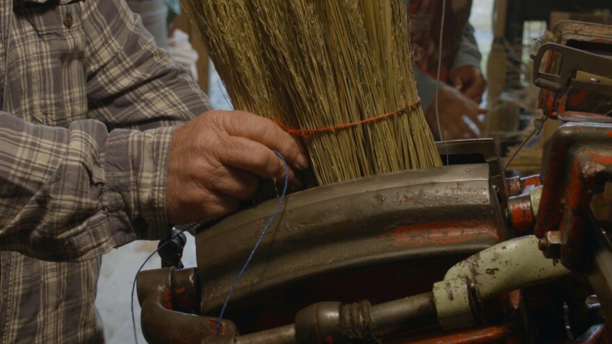 Wanda ties the broom corn while using the machine she purchased from Jim Shaffer.