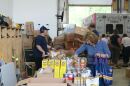 A person picks out something from a line of cans on a table at a food pantry.