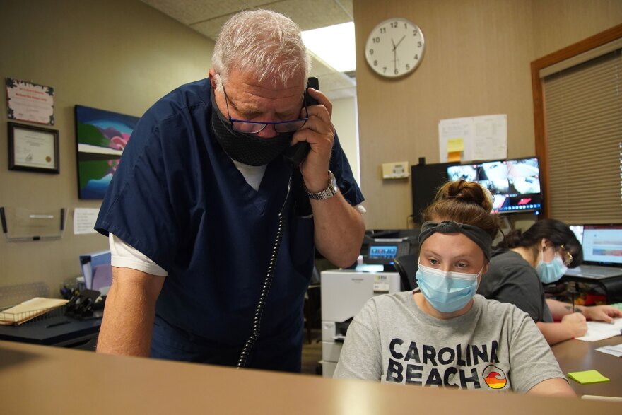 Dr. David Burkons talks with a patient on the phone alongside medical assistant Abby Ruggles inside the Northeast Ohio Women’s Center in Cuyahoga Falls on Friday.