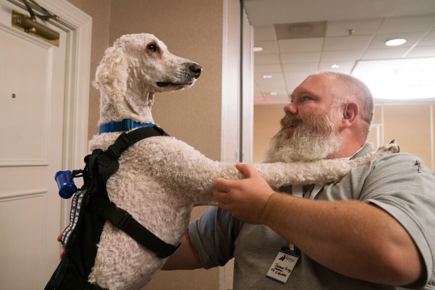 Navy veteran Thomas Gregg sits with his service dog, Gauge, at the conference.