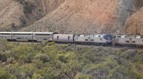 Two trains go down tracks through the mountains