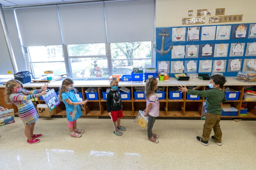 FILE - In this Oct. 6, 2020, file photo, kindergarten students check to make sure they are standing at the proper social distancing space as they line up to go outside during the coronavirus outbreak at the Osborn School, in Rye, N.Y. Schools and camps across the county are making plans to help kids catch up academically this summer after a year or more of remote learning for many of them. (AP Photo/Mary Altaffer, File)