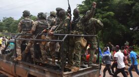 People celebrate in the streets with members of Guinea's armed forces after the arrest of Guinea's president, Alpha Conde, in a coup d'etat in Conakry on Sunday.