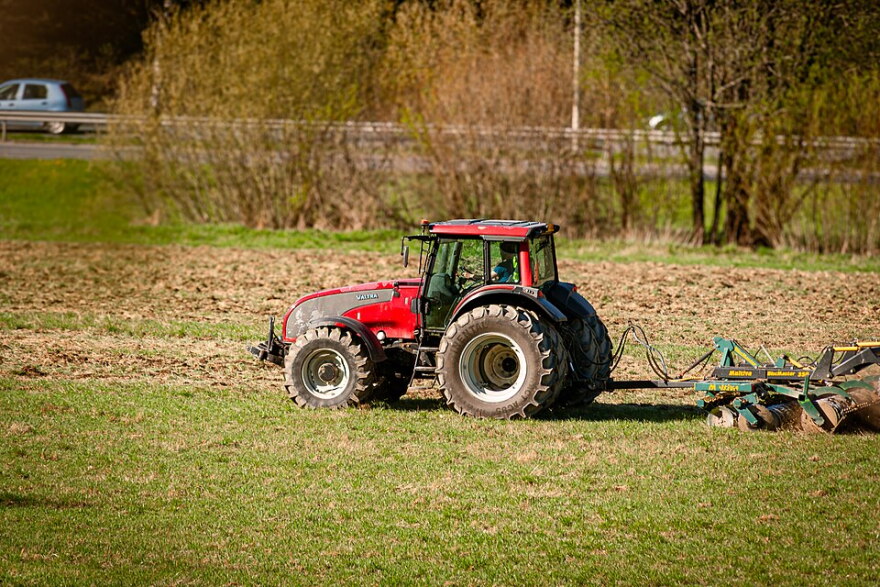 A red tractor in front of a red barn.