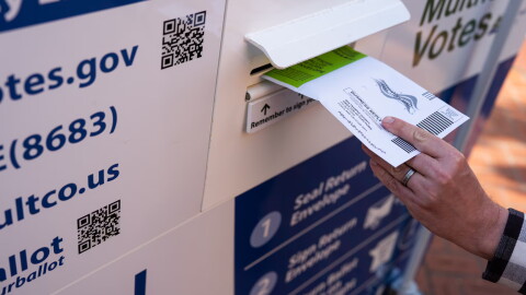 A voter drops off their ballot at a Multnomah County ballot drop box in Pioneer Courthouse Square in May 2026.