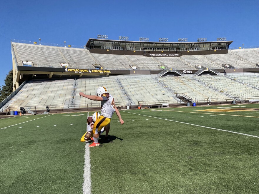 Cowboys kicker John Hoyland kicks a football in the empty Wyoming Cowboys football stadium.