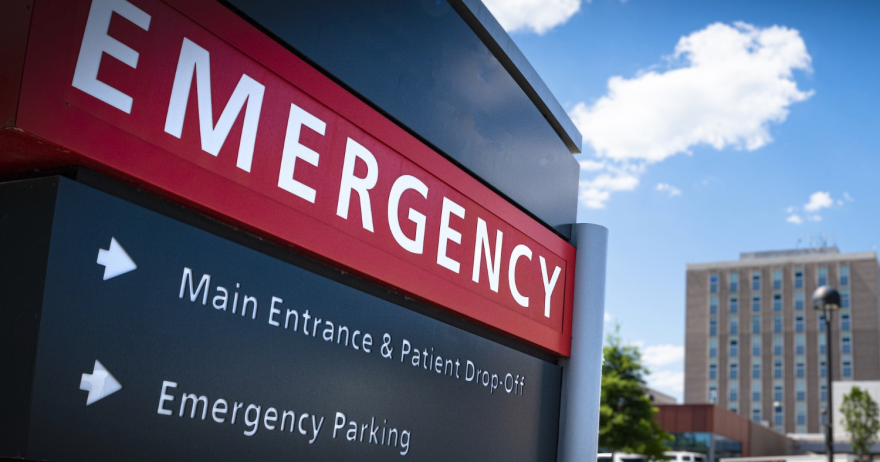 Close-up of a hospital emergency room sign that denotes the direction for emergency parking and the main entrance and patient drop-off.