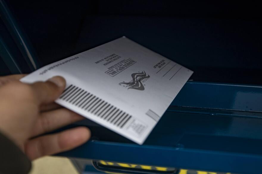 A voter places an election ballot in a ballot drop-off box in Somerville. (Jesse Costa/WBUR)