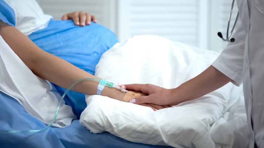 Doctor holding pregnant woman hand with catheter, birth defects prevention