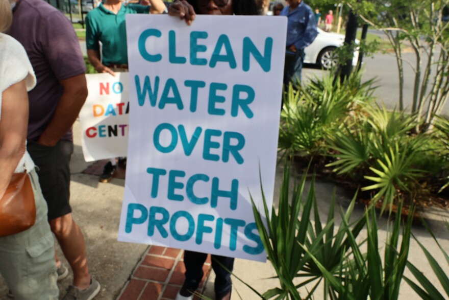 Protestor holds up a sign that reads "Clean Water Over Tech Profits"