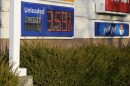 Closeup of electronic sign displaying the price of gas at $3.59 per gallon and attached to a pole behind bushes and next to a sign that reads 'polar pop'