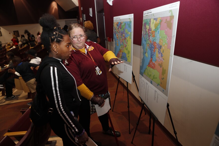 Two people, one an employee and another a student, looking at proposed school district maps for Hillsborough County. 