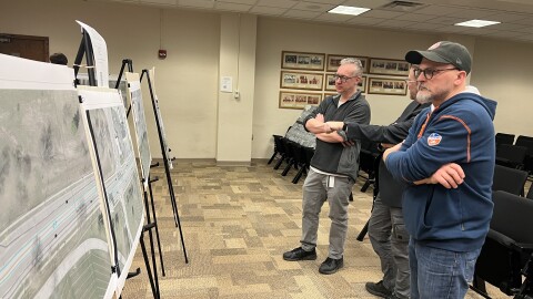 Three West Dayton community members gather around mock-ups of plans for reconstruction on W Third Street in Dayton's City Hall