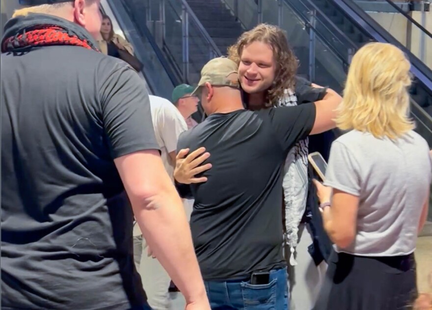 A man is hugged after exiting an escalator at Austin Bergstrom International Airport. 