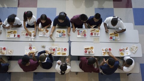 This stock photo shows students eating lunch at school.