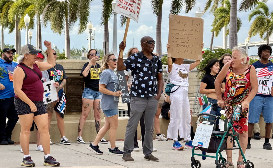 In middle with a black shirt, Ice Out Now protest organizer James Abraham of Babcock Ranch holds a sign reading "HATRED AND FEAR HAVE NO PLACE HERE," facing toward Bay Street.