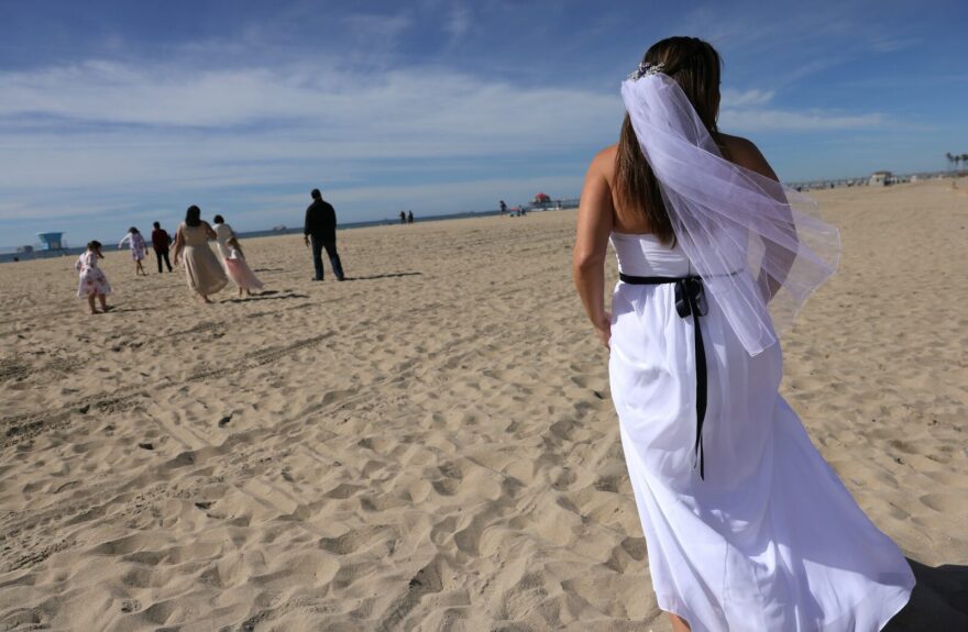 Bride Lorena James walks toward her wedding ceremony before she is married to husband Steven on the beach on Valentine’s Day in Huntington Beach, California.